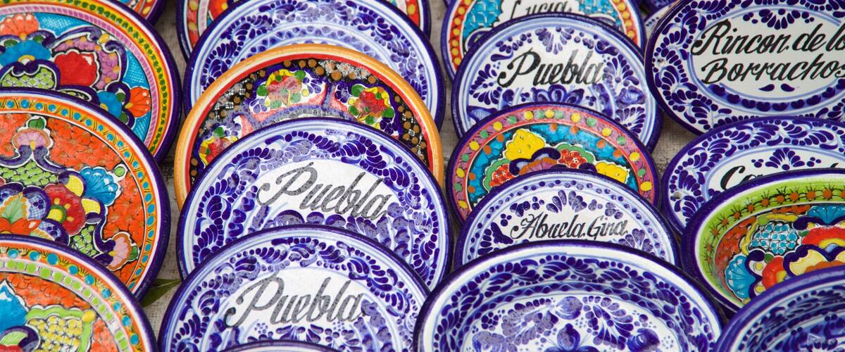 Une collection d’assiettes en céramique aux couleurs vives, ornées de motifs complexes et de textes.