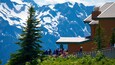 A group of people on a mountain trail with snow-capped mountains in the background.