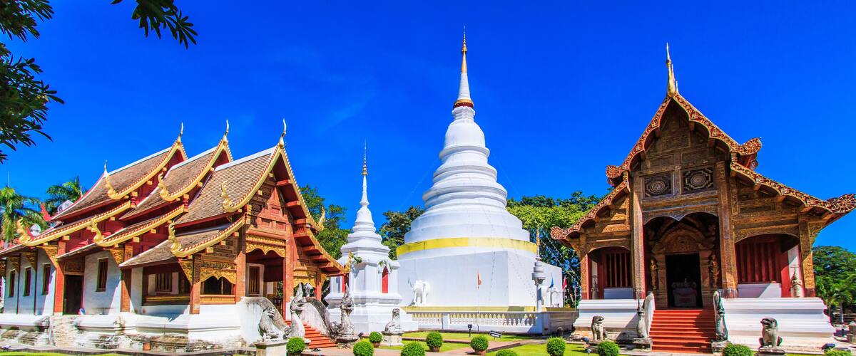 A temple complex with a central white stupa, red-roofed buildings, and intricate carvings.