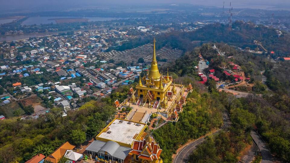 An aerial view of a town with a prominent golden temple surrounded by residential buildings and lush greenery.