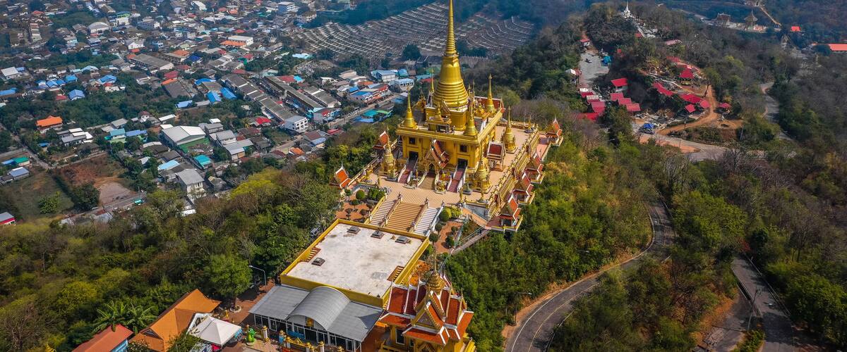 An aerial view of a town with a prominent golden temple surrounded by residential buildings and lush greenery.