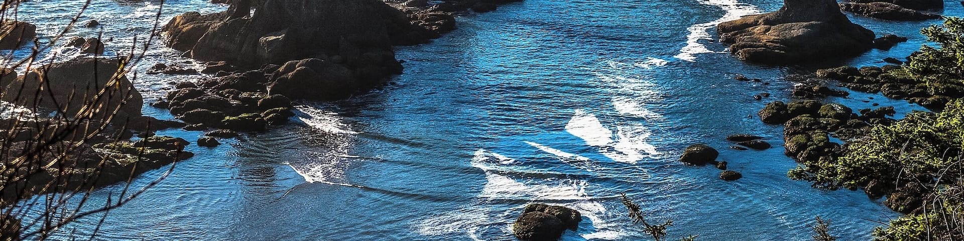 A rocky coastline with prominent rock formations and clear blue waters.