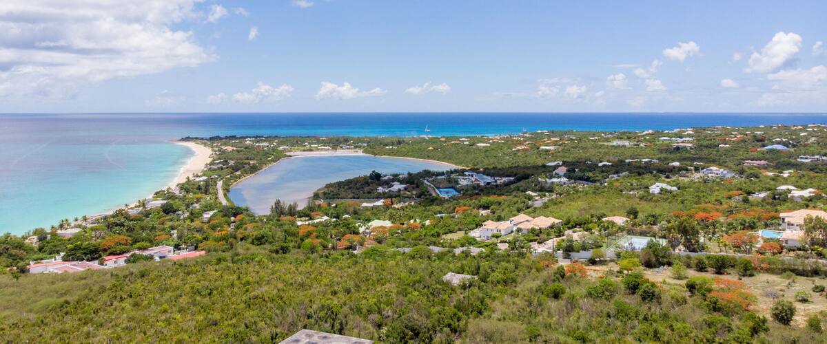 A coastal town with a beach, clear blue waters, and lush greenery.