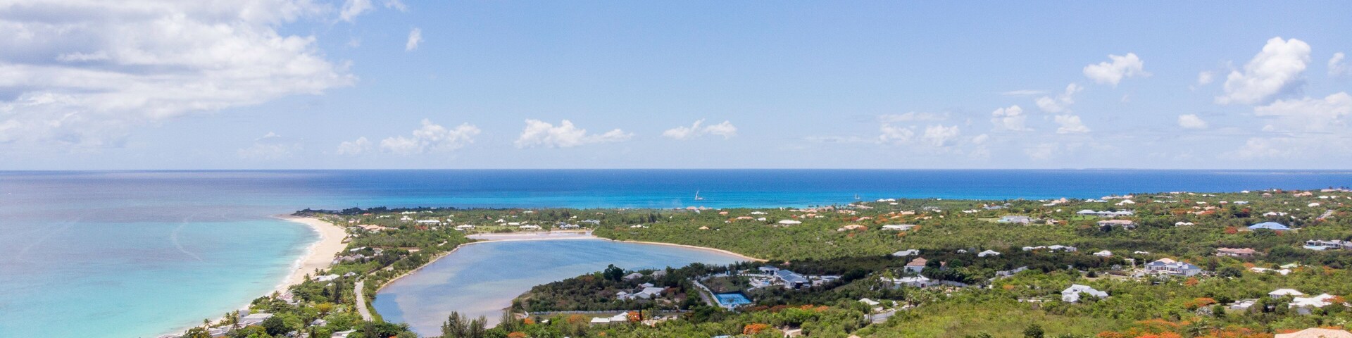 A coastal town with a beach, clear blue waters, and lush greenery.