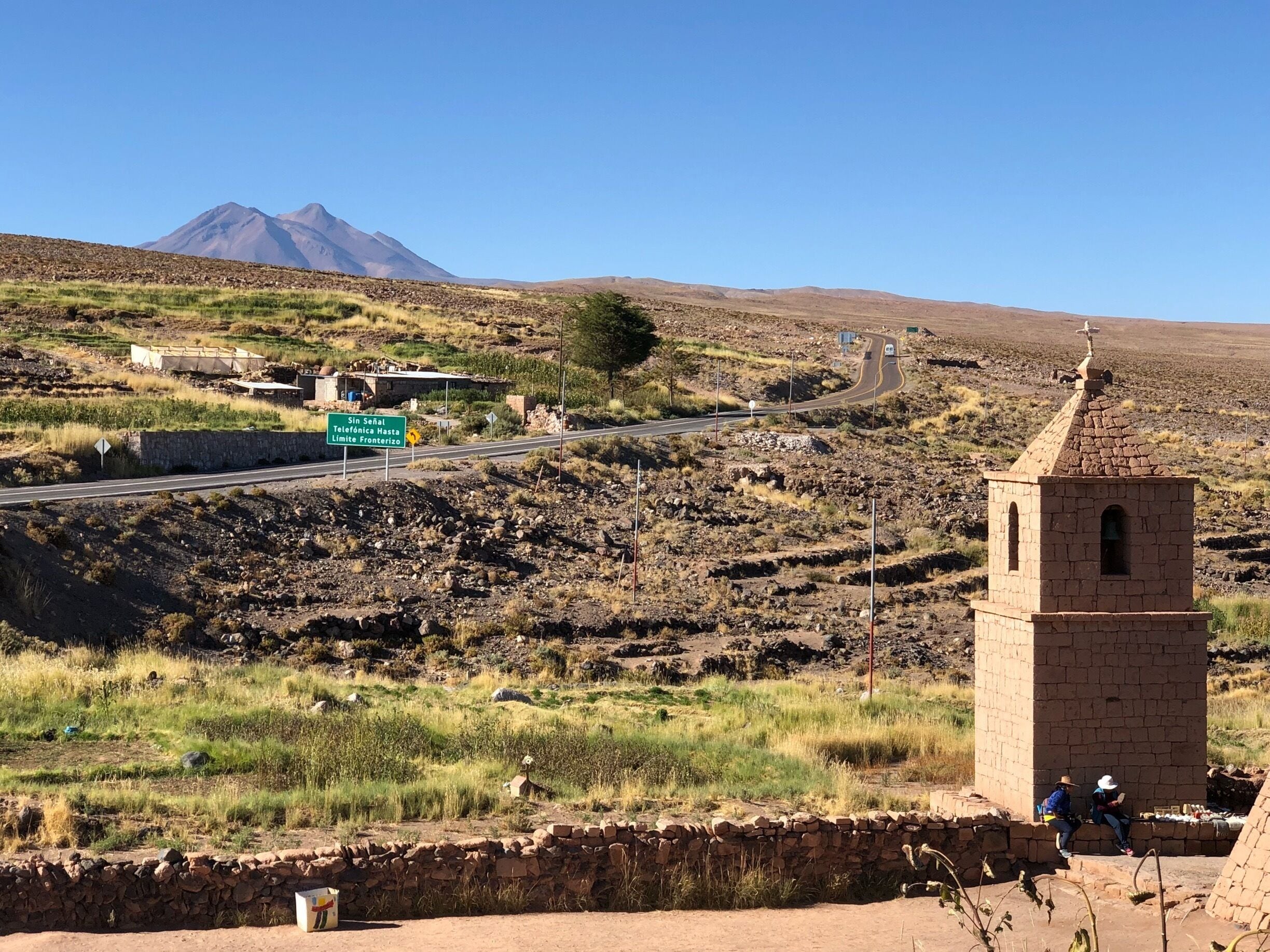 A rural landscape with a road, a stone tower, and a mountain in the background.