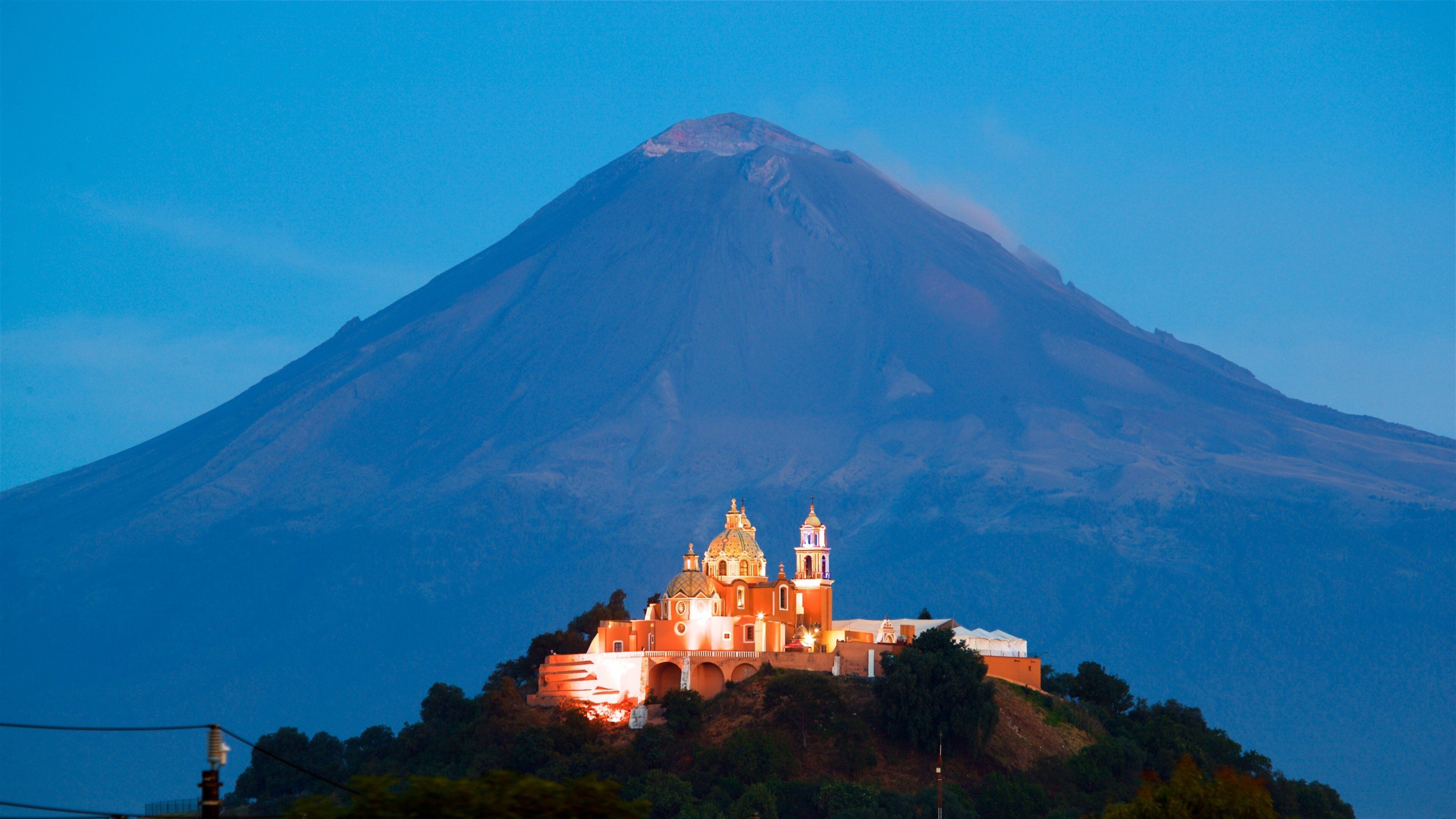 A church on a hill with a volcano in the background.