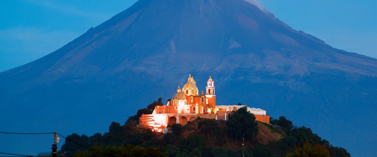 A church on a hill with a volcano in the background.