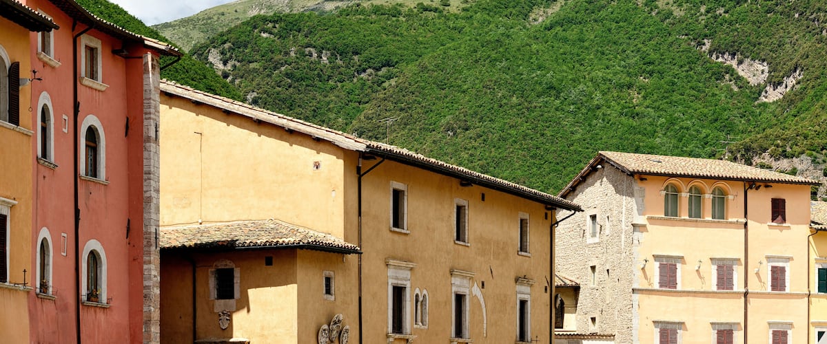 A village with colorful buildings and a green mountain in the background.