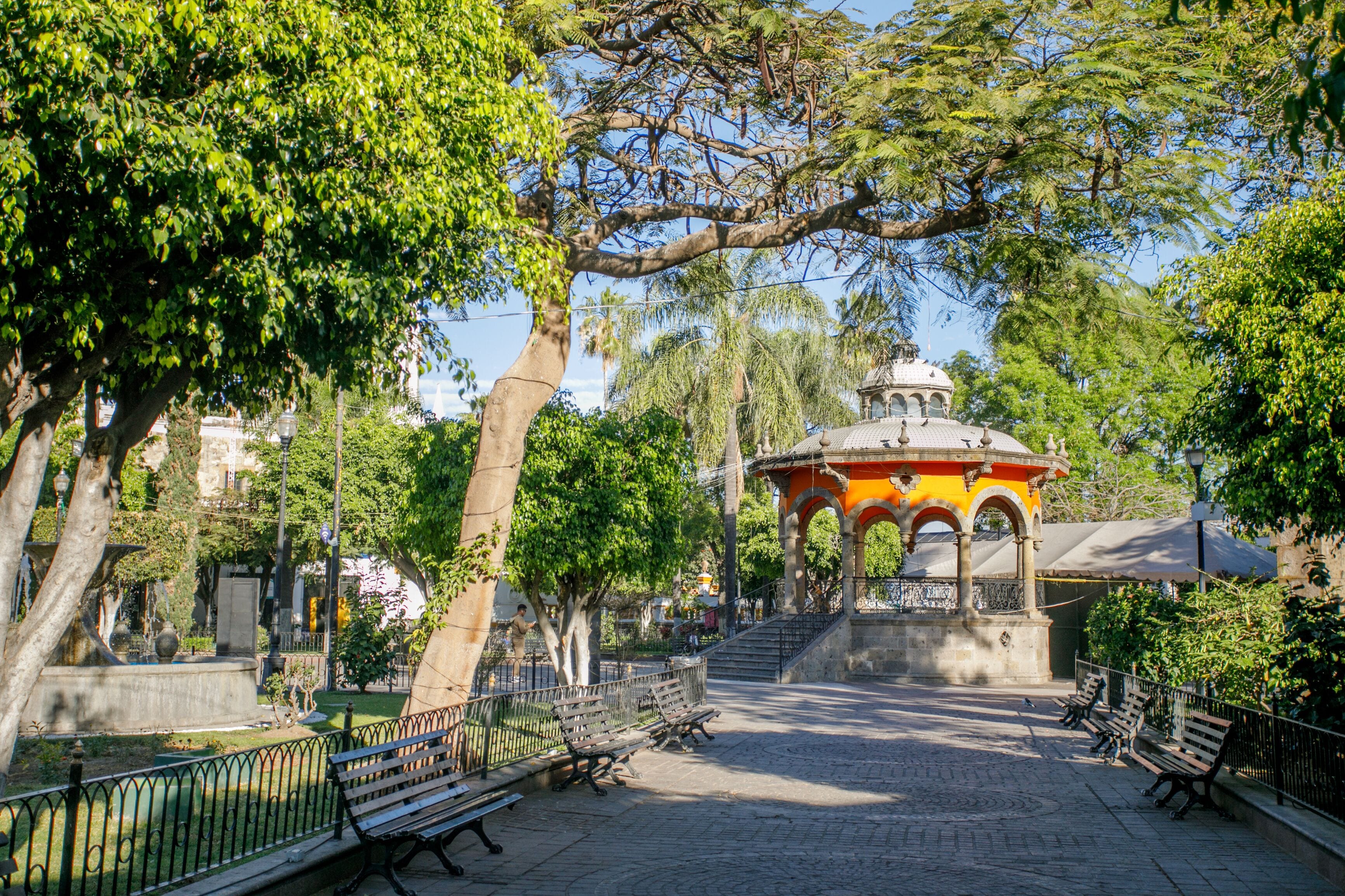 A park with a gazebo, benches, trees, and a fountain.