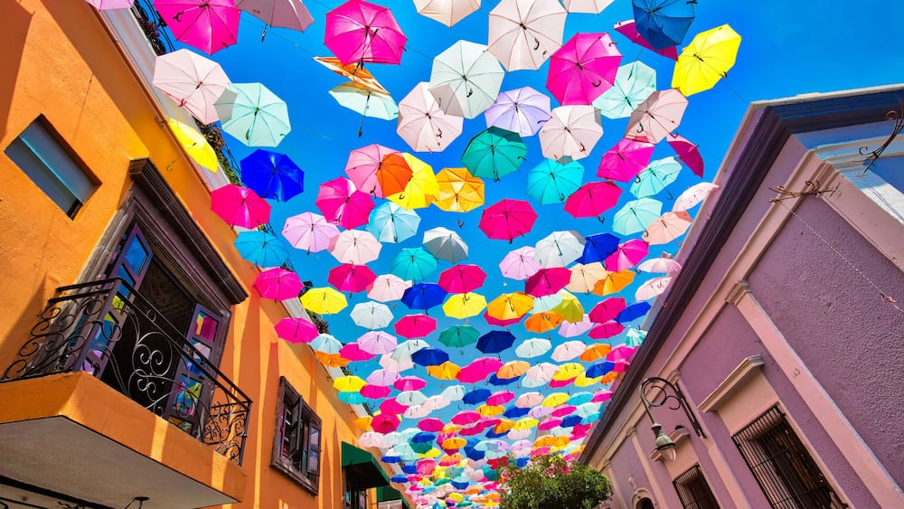 A street with colorful umbrellas suspended from the ceiling.