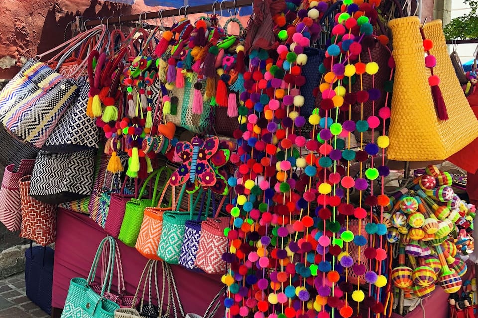 A market stall with colorful bags and hanging decorations.