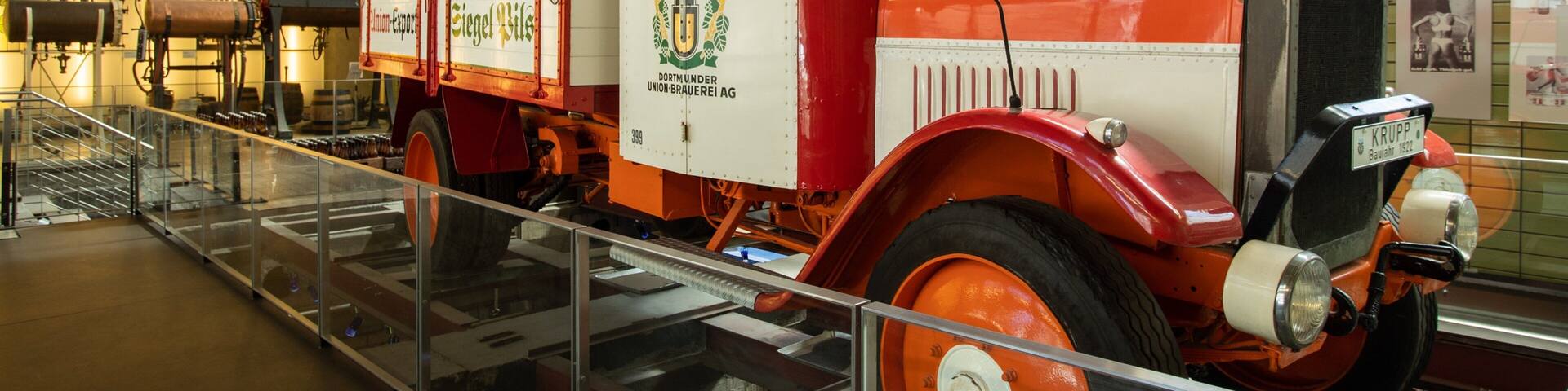 A vintage red and white truck with the text "Dortmunder Union Brauerei AG" and "Kruppe" on it.