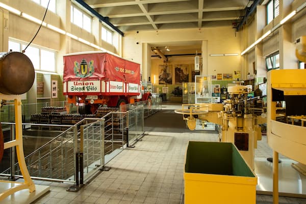A brewery interior with brewing equipment, barrels, and a large red truck labeled 'Union Siegf. Wils'.