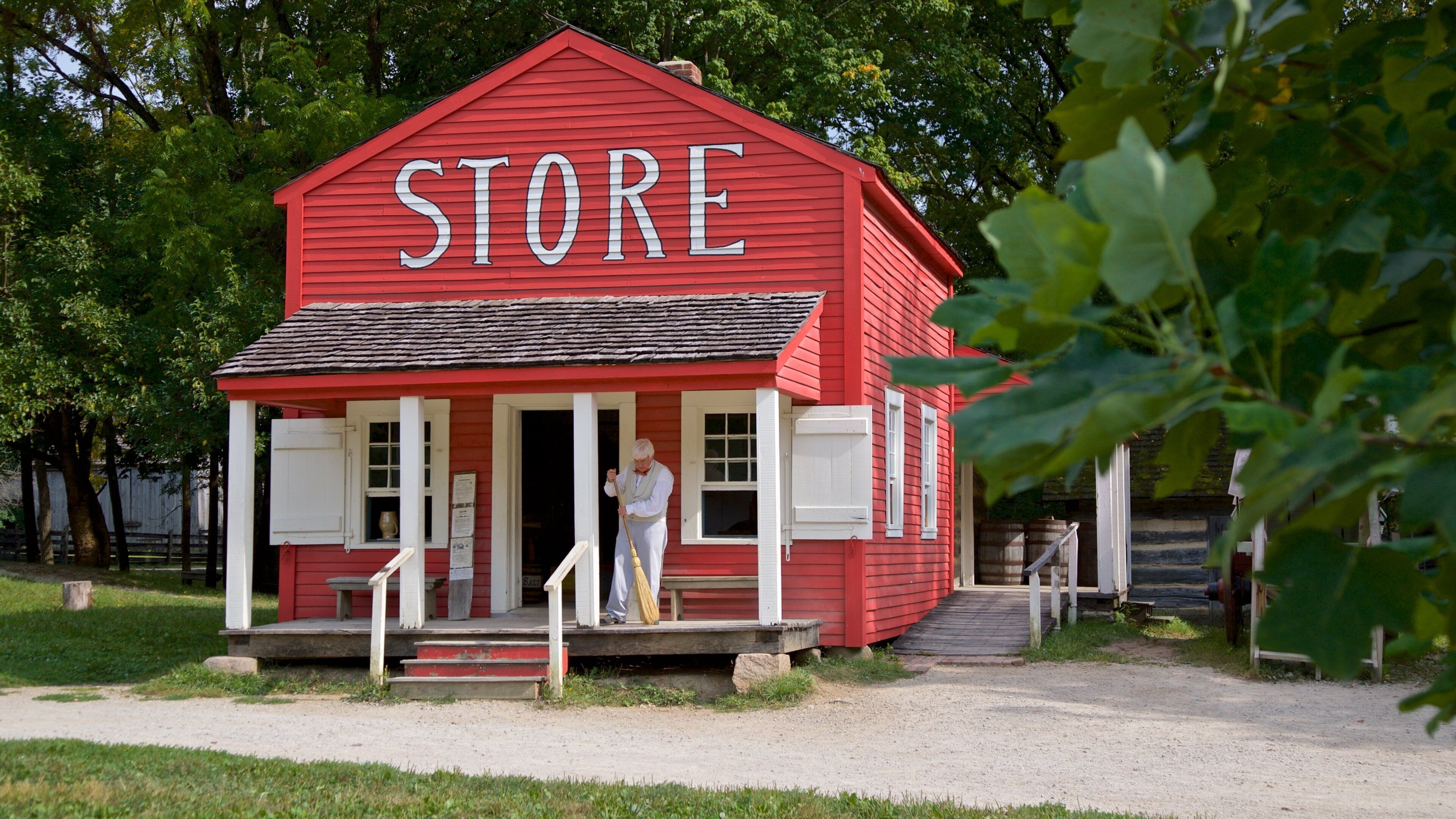 A red store with white trim and a person standing at the entrance.