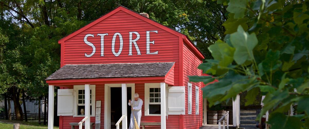 A red store with white trim and a person standing at the entrance.