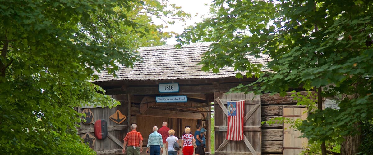 Ein hölzernes Gebäude mit einem Schild, auf dem „1816 Zwei Kulturen, Ein Land“ steht, und einer US-amerikanischen Flagge.