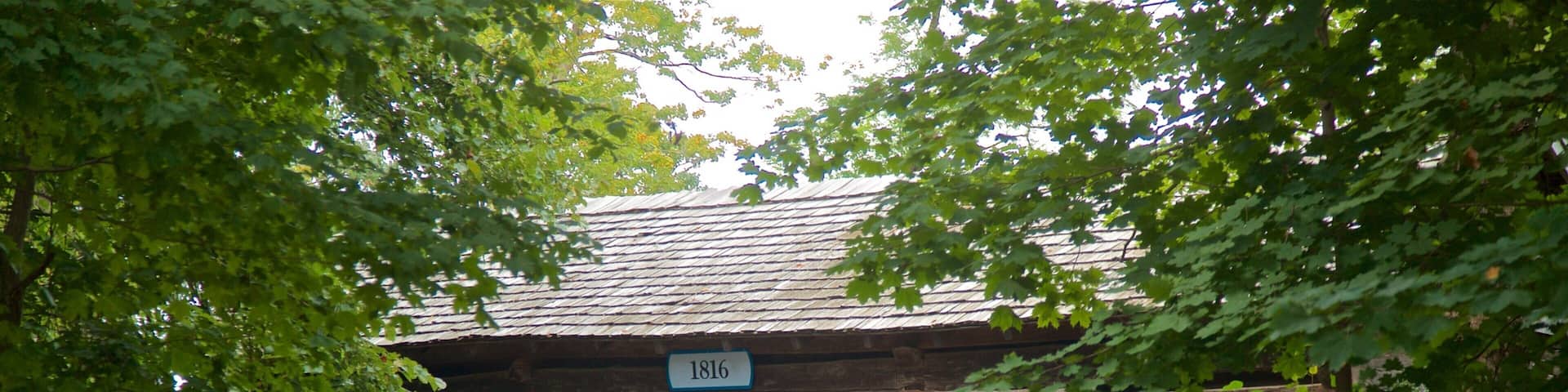 A wooden building with a sign reading "1816 Two Cultures, One Land" and an American flag.