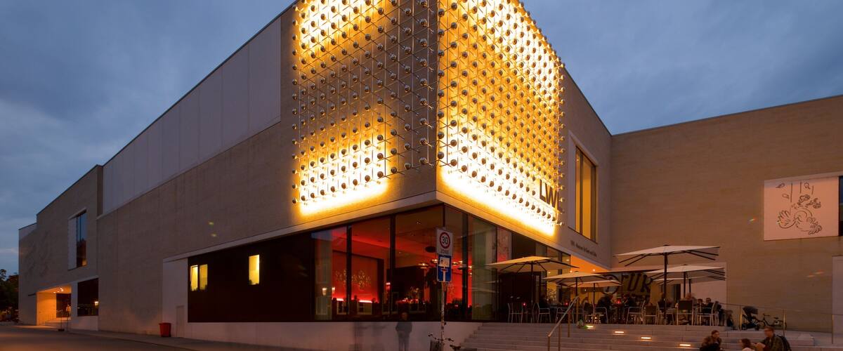 A modern building with a unique geometric facade and illuminated panels.