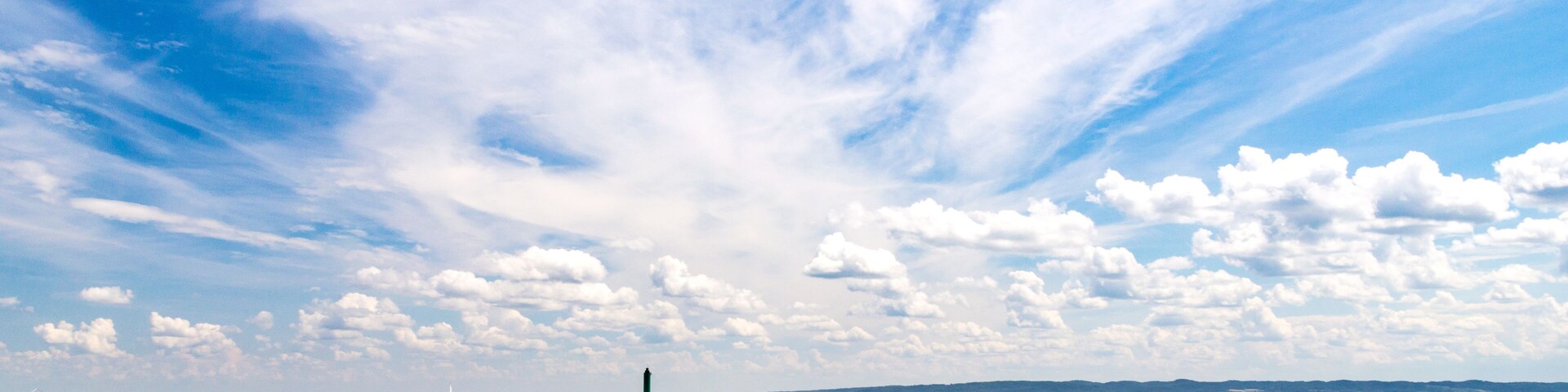 A pier extending into calm waters under a partly cloudy sky.