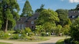 A large brick house surrounded by lush greenery and a well-maintained garden.