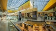 Un centre commercial moderne, doté de plusieurs niveaux, de rampes en verre et de nombreux magasins de vente au détail.