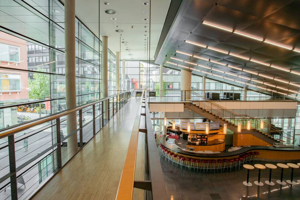 A modern indoor space with glass walls, a central bar area, and a staircase.