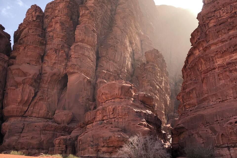 Une personne se tient debout dans un canyon désertique, entourée de formations rocheuses rouges.