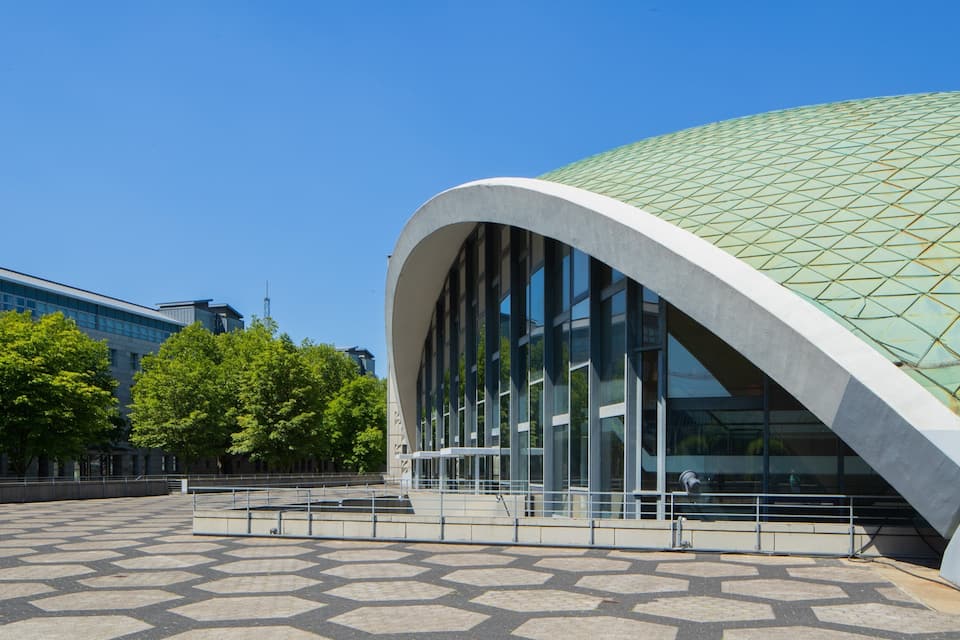 Un edifici modern amb façana de vidre corbat i teulada amb un disseny verd.