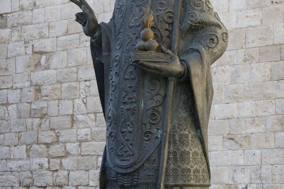 A statue of a robed figure holding a staff with a spherical object.