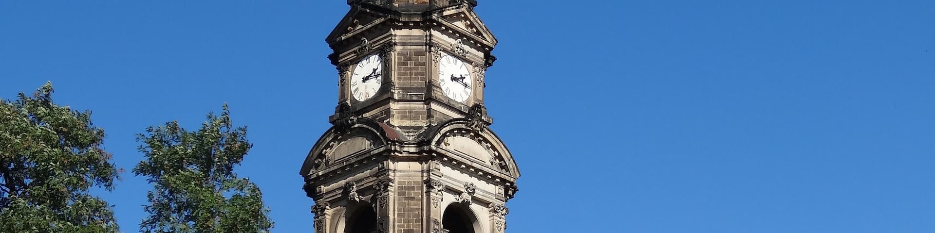 A historic church with a tall bell tower and two domes.