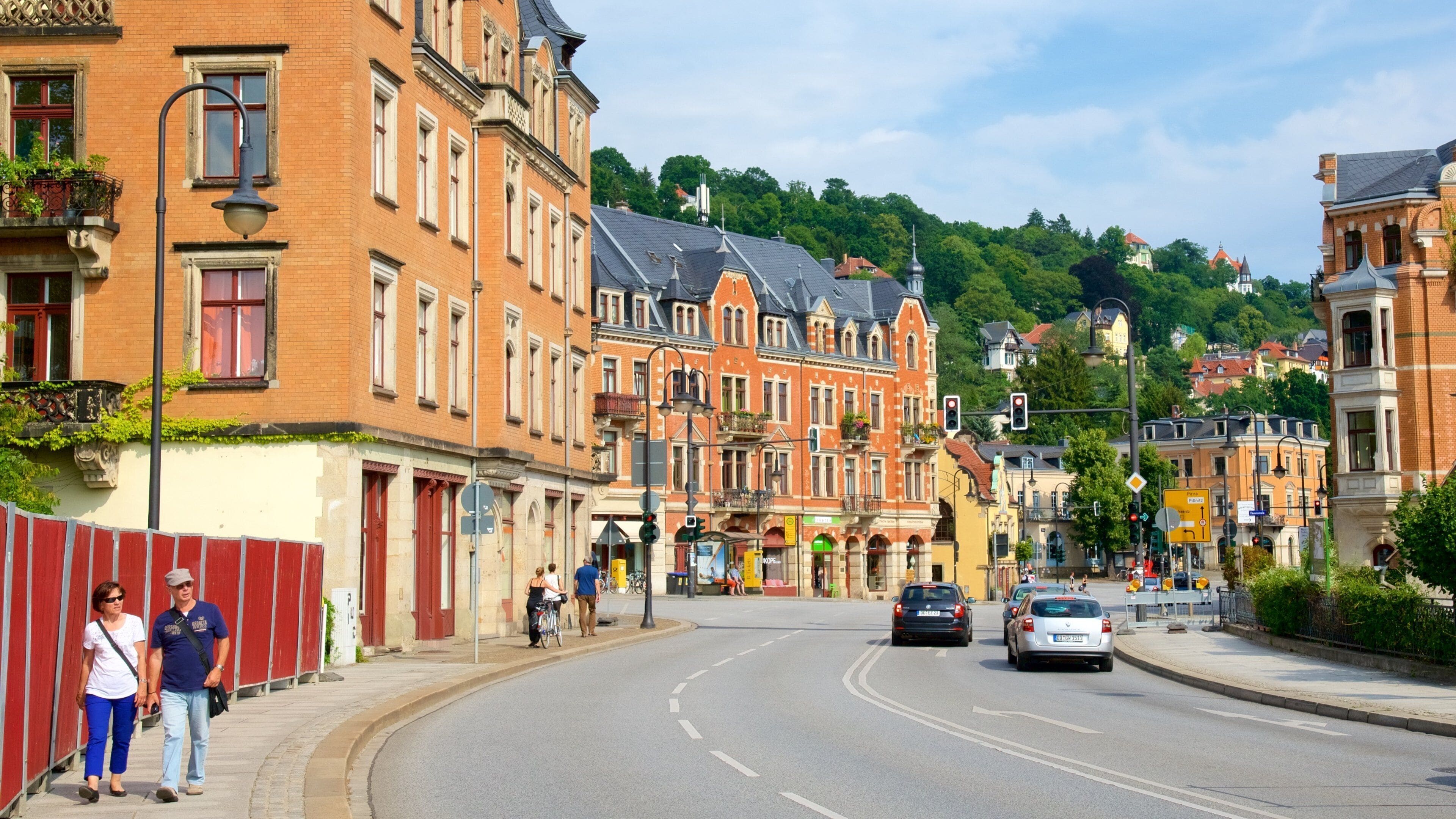 A street lined with historic buildings, a cyclist, and cars.