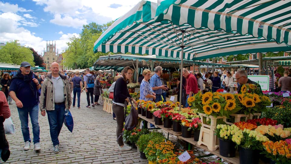 A bustling outdoor market with people browsing and buying flowers and plants.