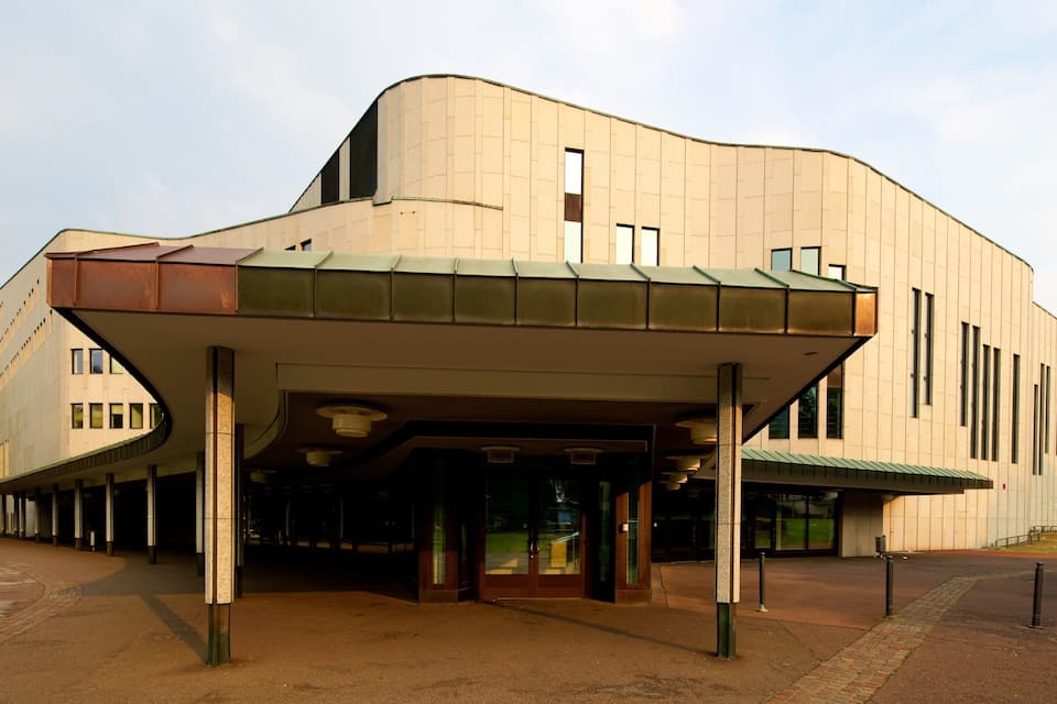 A modern building with a curved facade and a covered entrance.