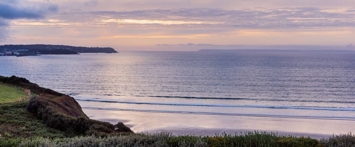 Côte de Douarnenez, mer calme, ciel nuageux, coucher de soleil imminent, atmosphère sereine et mystérieuse