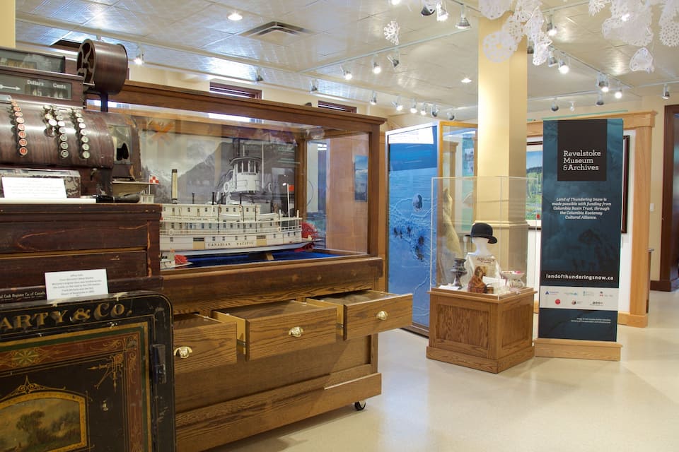 Una caja registradora antigua, un modelo del barco Canadian Pacific y una exhibición de artefactos históricos en un museo.