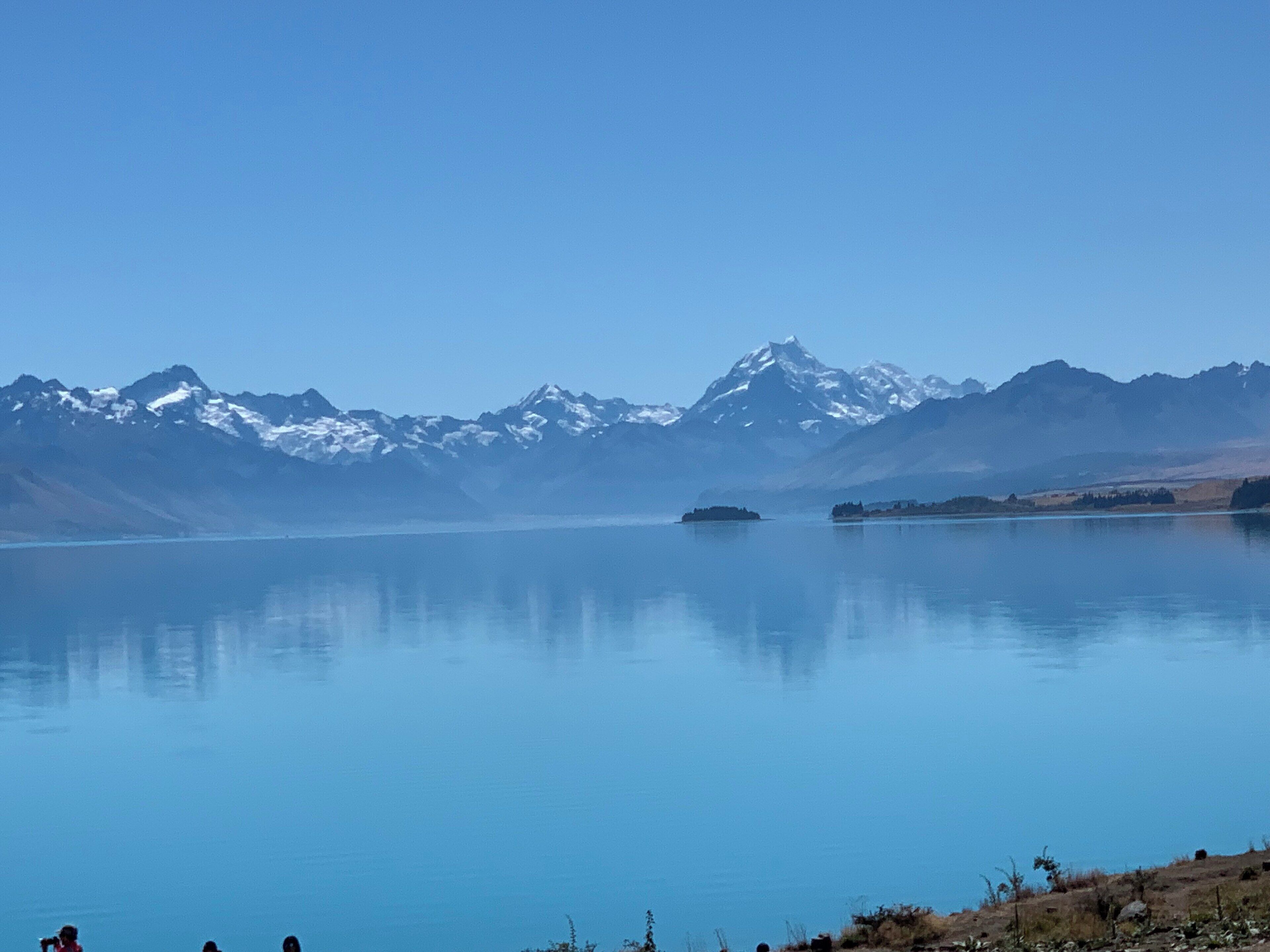 Un lago tranquilo con montañas nevadas al fondo.
