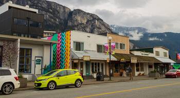 A street with colorful buildings, a yellow car, and a mountain in the background.