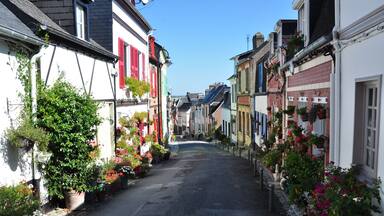 Une rue étroite bordée de bâtiments aux couleurs vives et de plantes en pot.