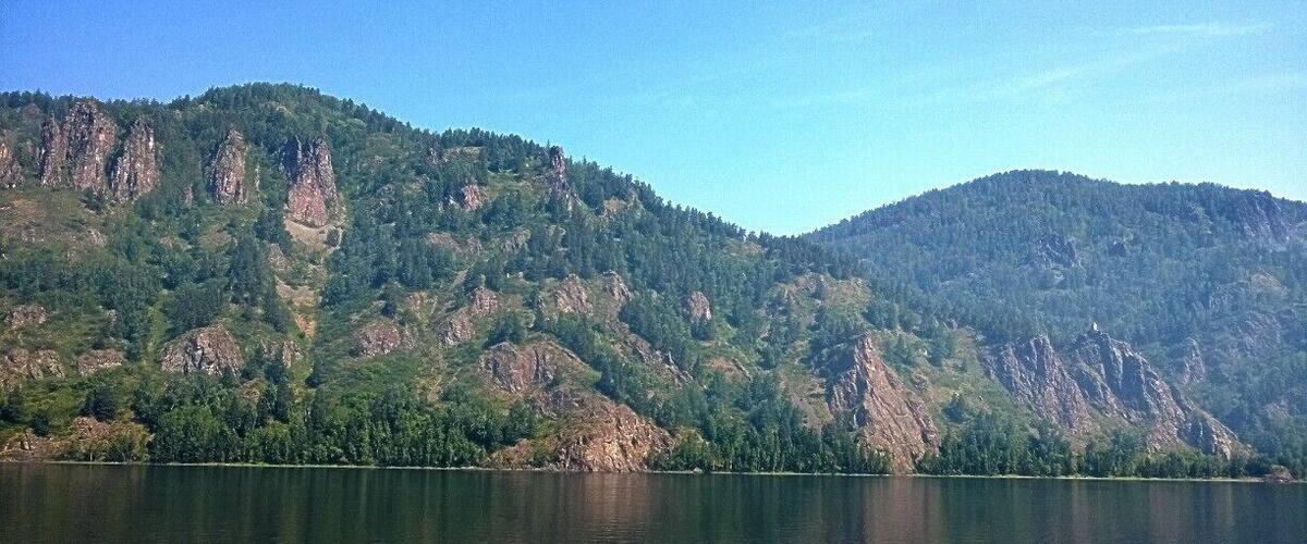 A calm lake surrounded by forested mountains.