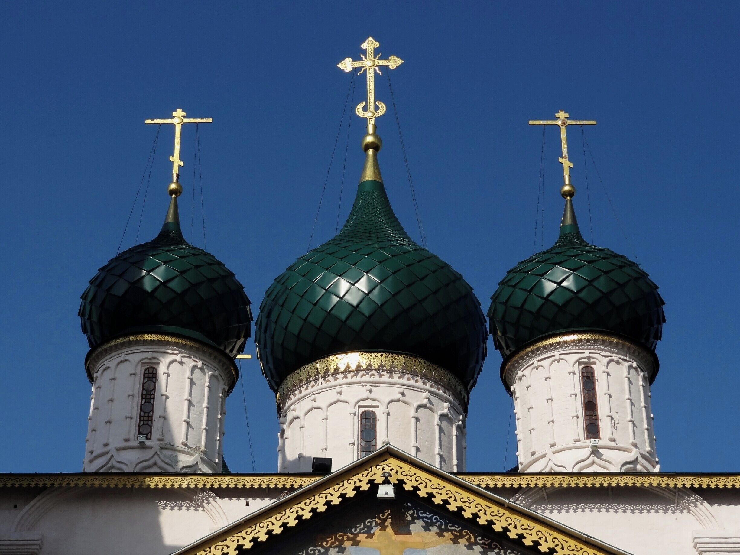 A church with three green domes and golden crosses.