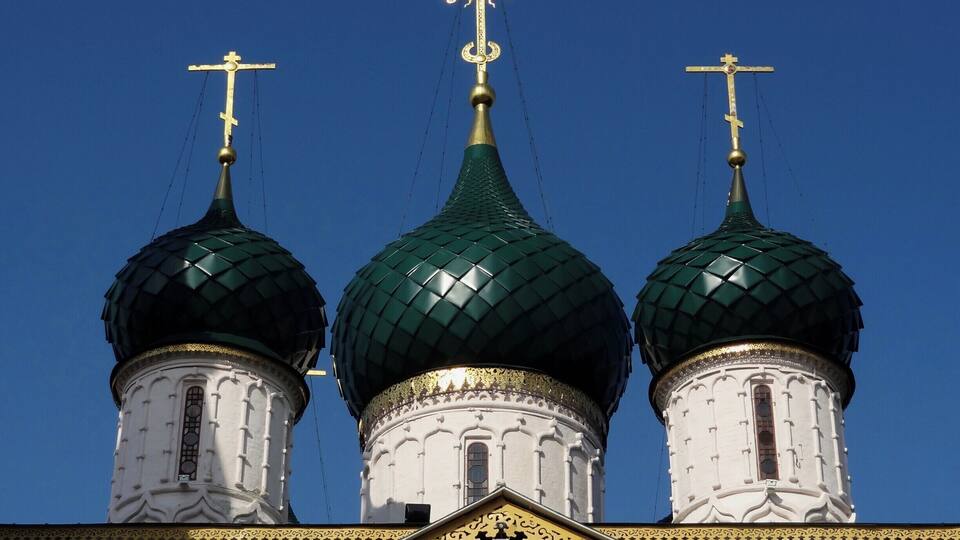 A church with three green domes and golden crosses.