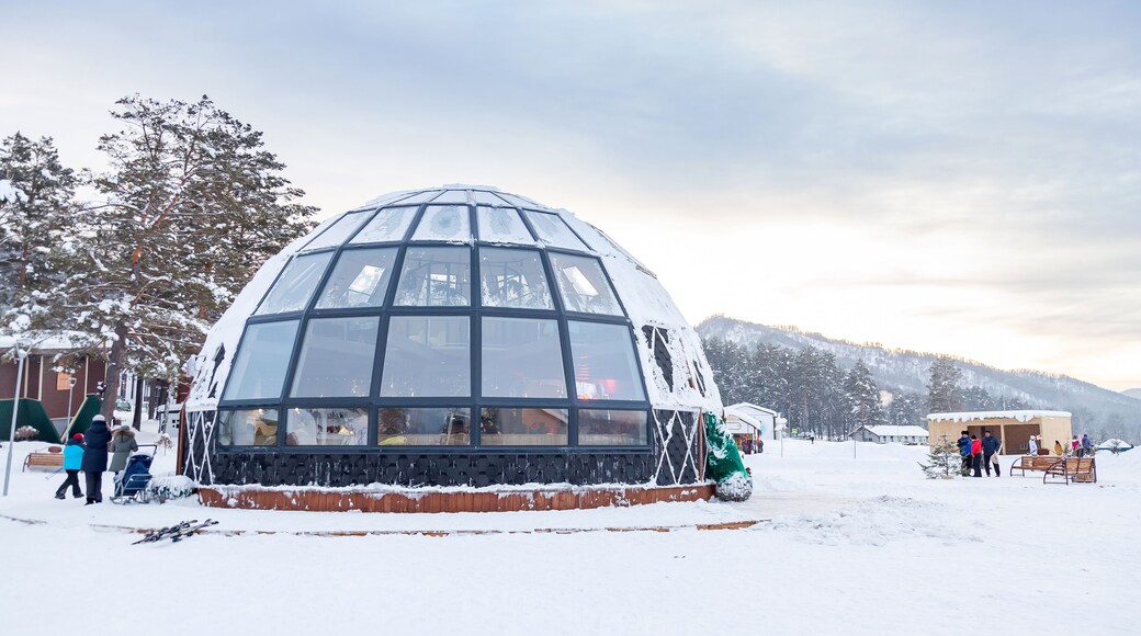 A beautiful cafe in the form of a hemisphere or a dome of glass and windows in winter with snow in the Altai mountains in the village of Manzherok.
