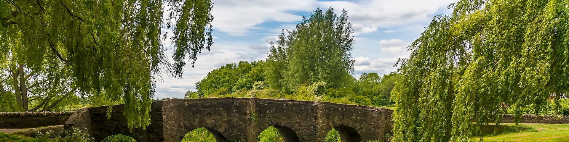 A view along the bank towards the old Packhorse Bridge on the outskirts of Anstey, Leicestershire in summertime