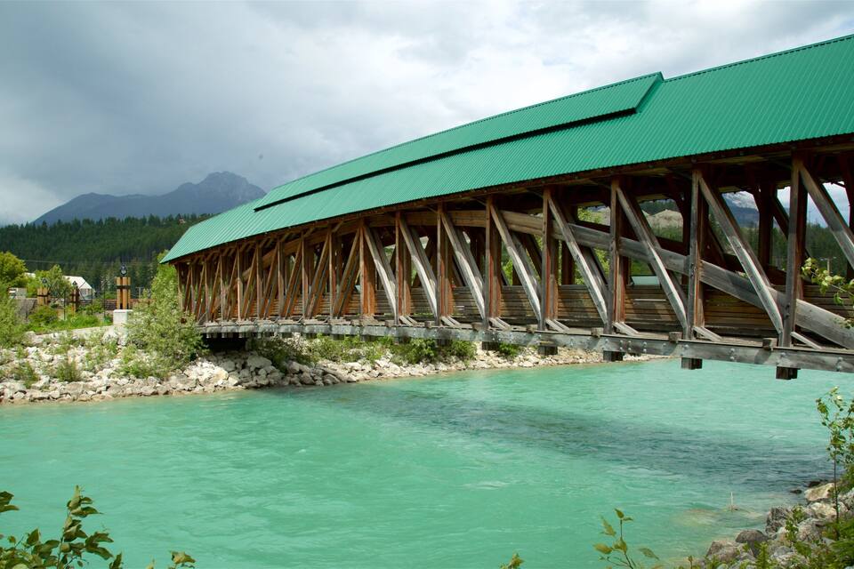 Un pont de fusta sobre un riu turquesa, amb muntanyes al fons.