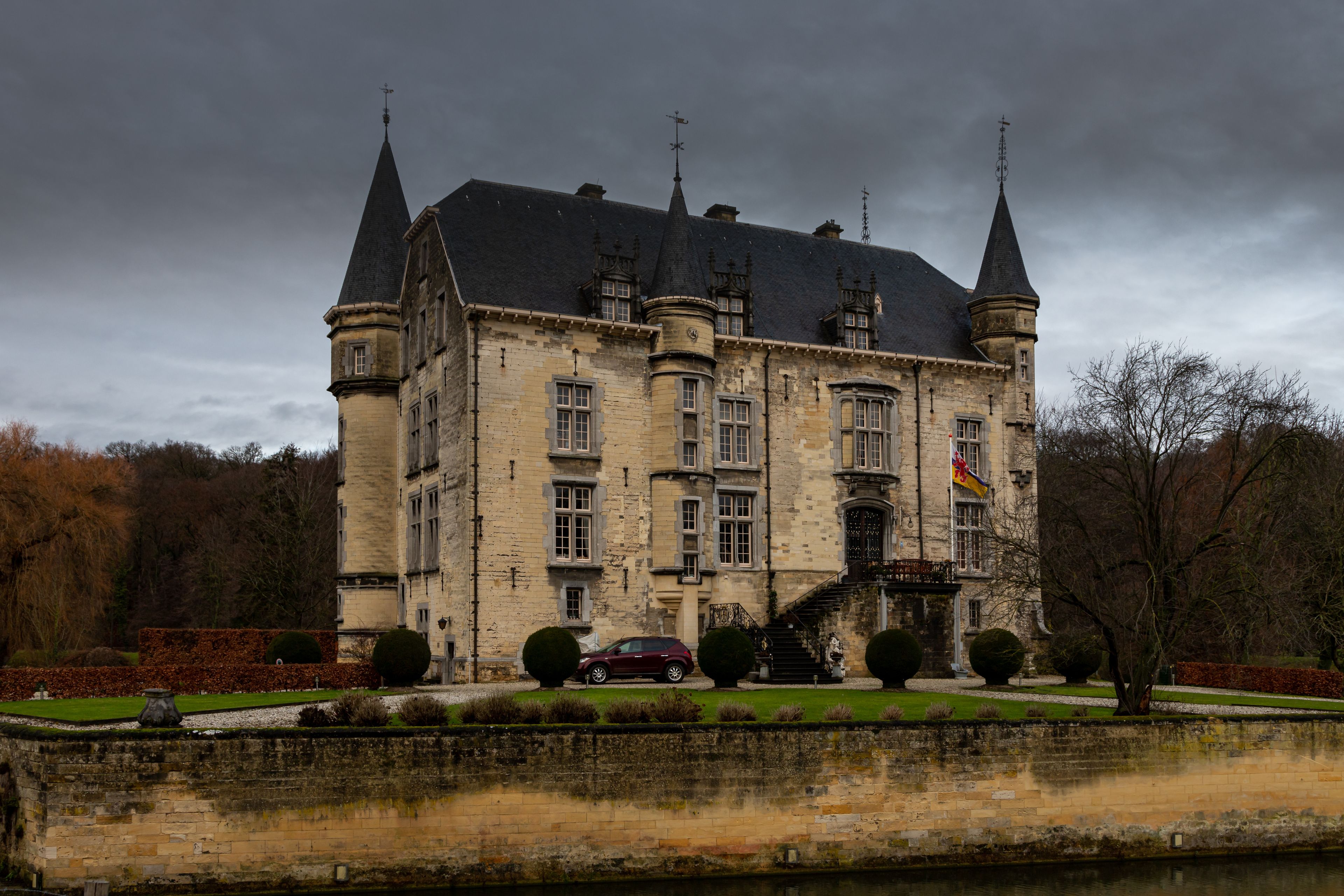 A large, historic stone building with multiple towers and a flag.