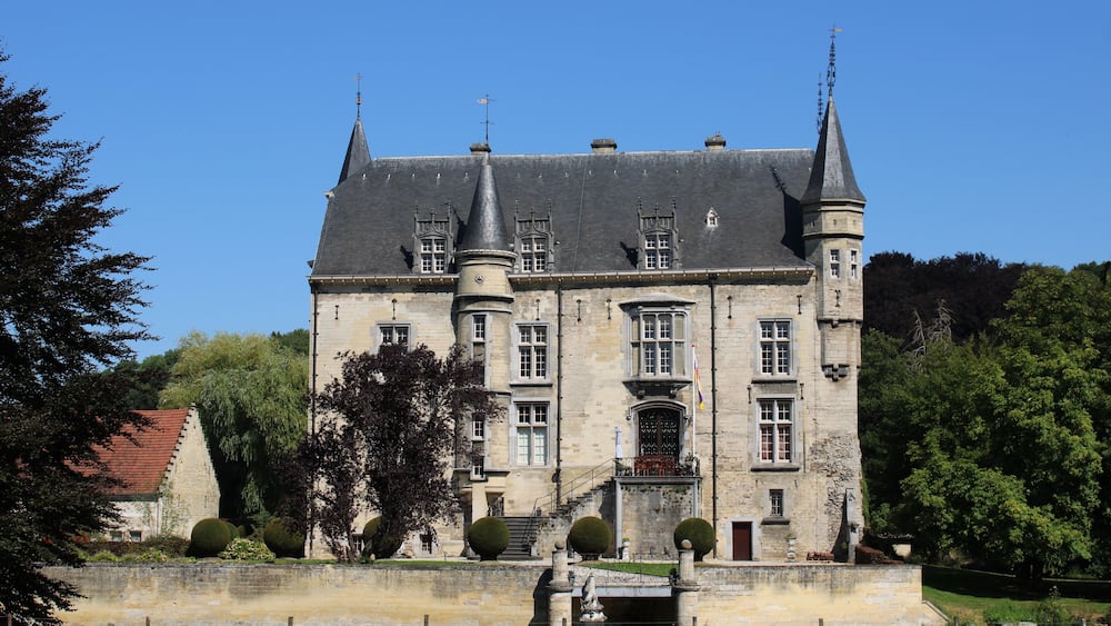 A large, historic castle with multiple towers and a well-maintained garden.