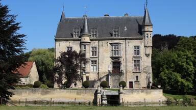 Een groot, historisch kasteel met meerdere torens en een verzorgde tuin.