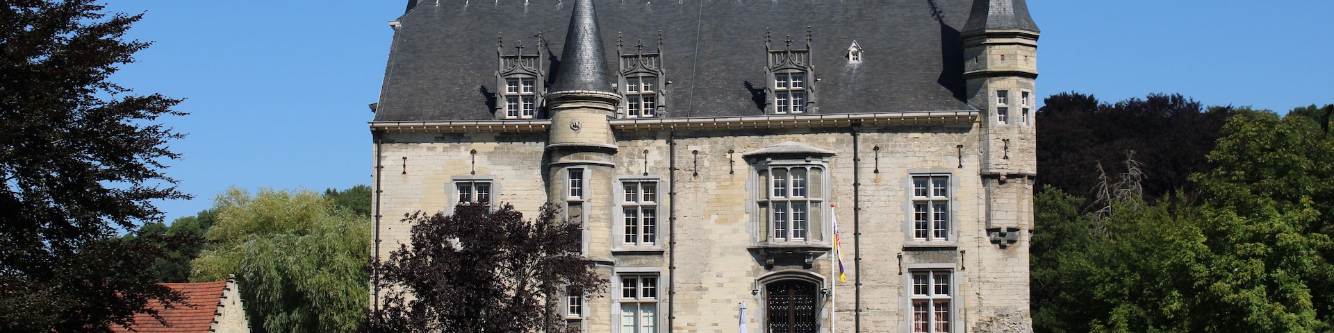 Un gran castillo histórico con múltiples torres y un jardín bien cuidado.