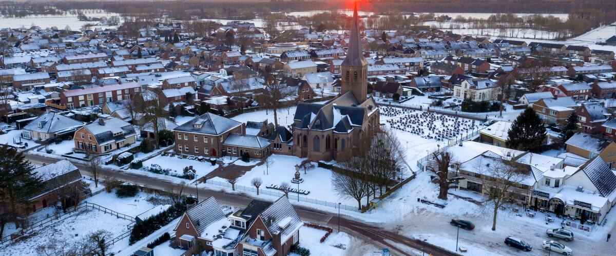 A snow-covered town with a prominent church steeple and a sunset in the background.