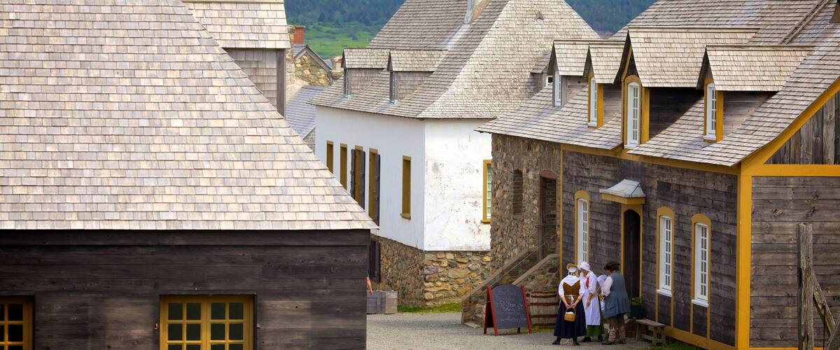 A village with traditional wooden houses, stone walls, and a clear sky.